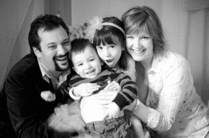 black and white portrait of smiling family tickling brother's belly