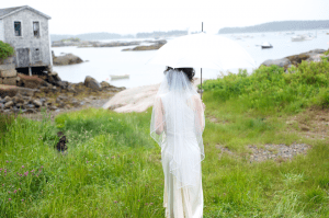 bride walks to ocean with umbrella