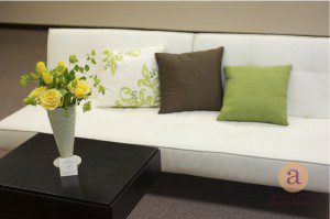 white couch with green pillows and yellow flowers