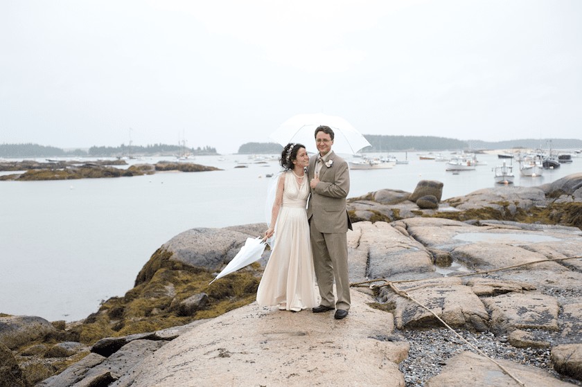 bride and groom share umbrella at the ocean