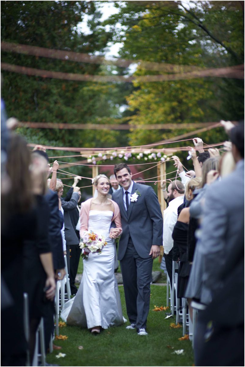 bride and groom walk under a ribbon canopy at ceremony
